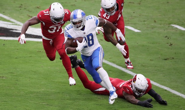 Running back Adrian Peterson #28 of the Detroit Lions rushes the football past Chris Banjo #31, Bud...