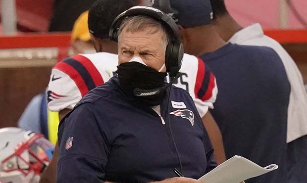 New England Patriots head coach Bill Belichick wears two masks as he watches from the sideline duri...