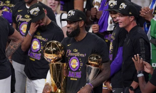 Los Angeles Lakers' LeBron James (23) holds the trophies as he celebrates with his teammates after ...