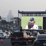 Clayton Kershaw of the Los Angeles Dodgers pitches as fans look on a giant screen during game one of the World Series between the Tampa Bay Rays and the Los Angeles Dodgers in the parking lot of Dodger Stadium in Los Angeles on Tuesday, October 20, 2020. (Keith Birmingham/The Orange County Register via AP)