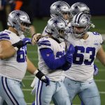 Dallas Cowboys' Brandon Knight (69) and Tyler Biadasz (63) walk off the field with running back Ezekiel Elliott (21) after Elliott fumbled the ball on a carry against the Arizona Cardinals in the first half of an NFL football game in Arlington, Texas, Monday, Oct. 19, 2020. (AP Photo/Ron Jenkins)