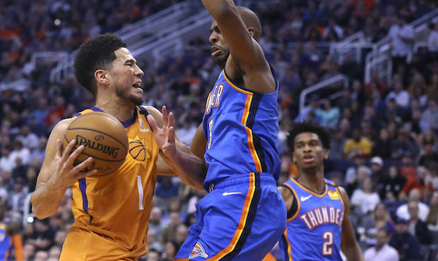 Oklahoma City Thunder guard Chris Paul, right front, stops Phoenix Suns guard Devin Booker (1) on h...