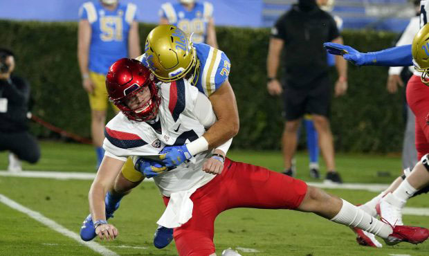 Arizona Wildcats quarterback Grant Gunnell, bottom, is tackled by UCLA linebacker Bo Calvert after ...