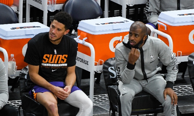Devin Booker #1 of the Phoenix Suns sits on the bench with teammate Chris Paul #3 during a game aga...