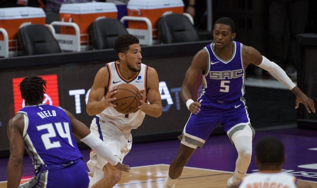 Phoenix Suns guard Devin Booker (1) works the ball past Sacramento Kings guard Buddy Hield (24) and...