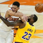 Phoenix Suns guard Devin Booker (1) passes over Los Angeles Lakers forward LeBron James (23) during the second half of a preseason NBA basketball game, Friday, Dec. 18, 2020, in Phoenix, Ariz. (AP Photo/Matt York)