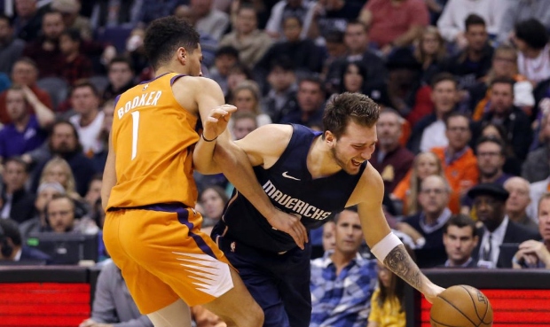 Dallas Mavericks forward Luka Doncic gets fouled by Phoenix Suns guard Devin Booker (1) during the ...