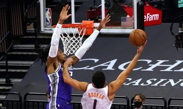 Phoenix Suns guard Devin Booker, right, goes to the basket against Sacramento Kings center Richaun ...