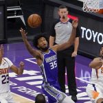Sacramento Kings forward Marvin Bagley III, center, goes up for a rebound between Phoenix Suns' Cameron Johnson, left, and Cameron Payne, right, during the second half of an NBA basketball game in Sacramento, Calif., Saturday, Dec. 26, 2020. The Kings won 106-103. (AP Photo/Rich Pedroncelli)