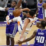 Phoenix Suns guard Devin Booker, center, loses the ball as he drives to the basket between Sacramento Kings' Buddy Hield, left, and Harrison Barnes during the second half of an NBA basketball game in Sacramento, Calif., Saturday, Dec. 26, 2020. The Kings won 106-103. (AP Photo/Rich Pedroncelli)