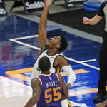 Utah Jazz guard Donovan Mitchell (45) lays up the ball as Phoenix Suns guard E'Twaun Moore (55) looks on during the first half of an NBA preseason basketball game Monday, Dec. 14, 2020, in Salt Lake City. (AP Photo/Rick Bowmer)
