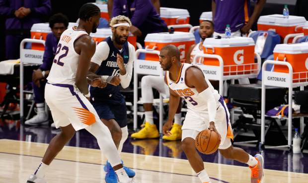 PHOENIX, ARIZONA - DECEMBER 23: Chris Paul #3 of the Phoenix Suns handles the ball as Deandre Ayton...