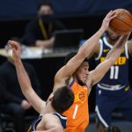 Phoenix Suns guard Devin Booker pulls in a rebound as Denver Nuggets center Nikola Jokic defends during the second half of an NBA basketball game Friday, Jan. 1, 2021, in Denver. The Suns won 106-103. (AP Photo/David Zalubowski)