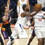 Los Angeles Clippers forward Paul George, center, drives to the basket past the defense of Phoenix Suns' Dario Saric, left, during the first half of an NBA basketball game Sunday, Jan. 3, 2021, in Phoenix. (AP Photo/Ralph Freso)