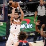 Phoenix Suns guard Devin Booker (1) shoots against Washington Wizards center Robin Lopez (15) and guard Bradley Beal (3) during the first half of an NBA basketball game, Monday, Jan. 11, 2021, in Washington. (AP Photo/Nick Wass)