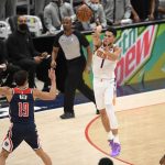Phoenix Suns guard Devin Booker (1) passes the ball against Washington Wizards guards Raul Neto (19) and Bradley Beal (3) during the first half of an NBA basketball game, Monday, Jan. 11, 2021, in Washington. (AP Photo/Nick Wass)