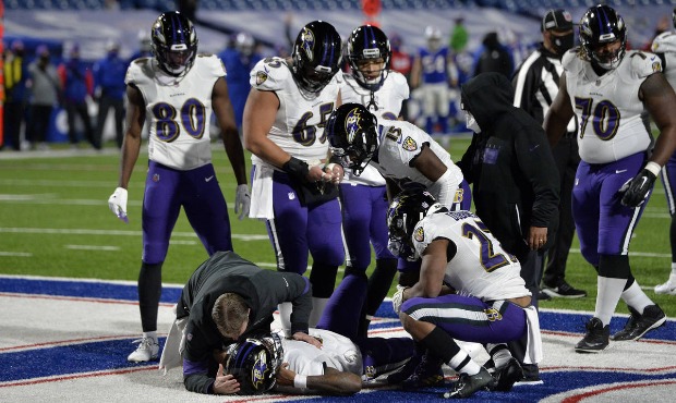 A trainer checks on Baltimore Ravens quarterback Lamar Jackson, below, after he was injured during ...