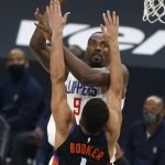 Los Angeles Clippers forward Serge Ibaka (9) shoots over the defense of Phoenix Suns guard Devin Booker (1) during the first half of an NBA basketball game Sunday, Jan. 3, 2021, in Phoenix. (AP Photo/Ralph Freso)