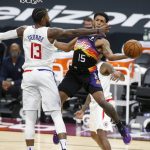 Phoenix Suns guard Cameron Payne (15) attempts to pass the ball around the defense of Los Angeles Clippers forward Paul George (13) during the second half of an NBA basketball game Sunday, Jan. 3, 2021, in Phoenix. (AP Photo/Ralph Freso)