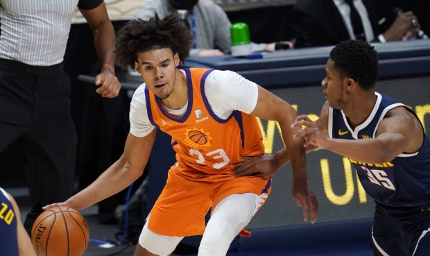 Phoenix Suns forward Cameron Johnson looks to pass the ball as Denver Nuggets guard PJ Dozier defen...