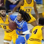 UCLA guard Tyger Campbell, middle, tries to drive between Arizona State guard Holland Woods (0) and forward Kimani Lawrence (4) during the first half of an NCAA college basketball game Thursday, Jan. 7, 2021, in Tempe, Ariz. (AP Photo/Ross D. Franklin)
