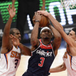 Washington Wizards guard Bradley Beal, center, goes to the basket between Phoenix Suns guards Chris Paul, left, and Devin Booker (1) during the second half of an NBA basketball game, Monday, Jan. 11, 2021, in Washington. (AP Photo/Nick Wass)