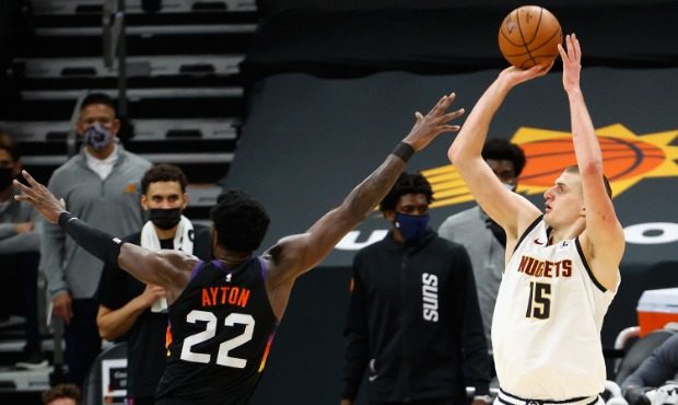 Nikola Jokic #15 of the Denver Nuggets attempts a shot over Deandre Ayton #22 of the Phoenix Suns d...