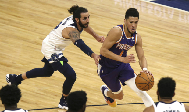 Phoenix Suns' Devin Booker (1) drives the ball past Minnesota Timberwolves' Ricky Rubio (9) in the ...
