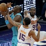 Charlotte Hornets center Bismack Biyombo is fouled by Phoenix Suns guard Cameron Payne (15) as forward Jae Crowder (99) looks on during the second half of an NBA basketball game, Wednesday, Feb. 24, 2021, in Phoenix. (AP Photo/Matt York)
