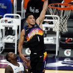Phoenix Suns guard Devin Booker (1) dunks over Orlando Magic forward Gary Clark during the first half of an NBA basketball game Sunday, Feb. 14, 2021, in Phoenix. (AP Photo/Rick Scuteri)