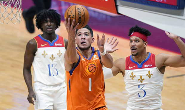 Phoenix Suns guard Devin Booker (1) drives to the basket in front of New Orleans Pelicans guard Jos...