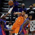 Phoenix Suns guard Devin Booker (1) passes over Detroit Pistons forward Jerami Grant, left, during the first half of an NBA basketball game, Friday, Feb. 5, 2021, in Phoenix. (AP Photo/Matt York)