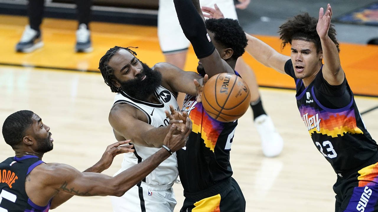 Brooklyn Nets guard James Harden dishes around Phoenix Suns center Deandre Ayton, right, during the...