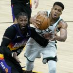 Milwaukee Bucks forward Giannis Antetokounmpo, right, and Phoenix Suns forward Jae Crowder (99) try to get possession of the ball during the second half of an NBA basketball game Wednesday, Feb. 10, 2021, in Phoenix. (AP Photo/Matt York)
