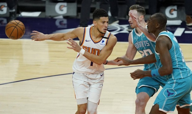 Phoenix Suns guard Devin Booker (1) dishes off as Charlotte Hornets forward Gordon Hayward (20) def...