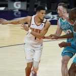 Phoenix Suns guard Devin Booker (1) dishes off as Charlotte Hornets forward Gordon Hayward (20) defends during the second half of an NBA basketball game, Wednesday, Feb. 24, 2021, in Phoenix. (AP Photo/Matt York)