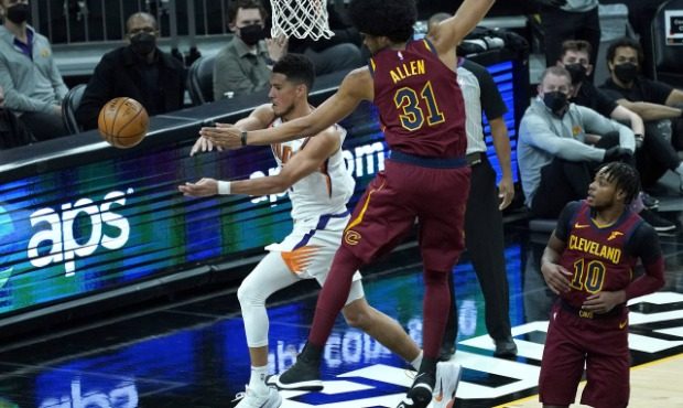 Phoenix Suns guard Devin Booker dishes off around Cleveland Cavaliers center Jarrett Allen (31) dur...