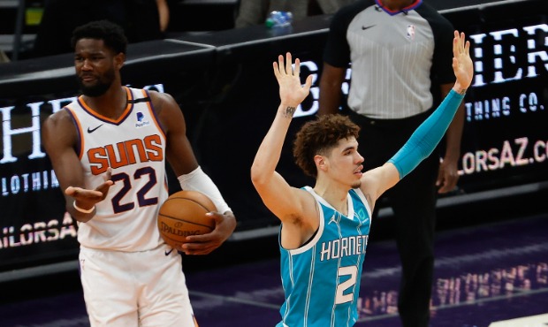 LaMelo Ball #2 of the Charlotte Hornets reacts to a slam dunk ahead of Deandre Ayton #22 of the Pho...