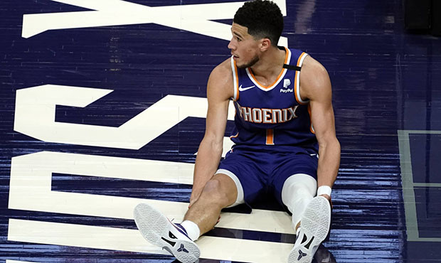 Phoenix Suns guard Devin Booker watches as play continues after he was knocked to the floor during ...