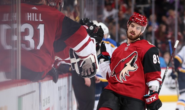 Conor Garland #83 of the Arizona Coyotes celebrates with teammates on the bench after scoring a pow...