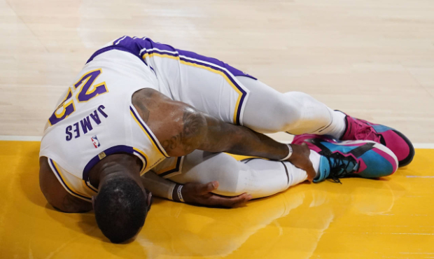 Los Angeles Lakers forward LeBron James holds his ankle after going down with an injury during the ...