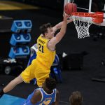 
              Michigan guard Franz Wagner (21) drives to the basket over UCLA forward Kenneth Nwuba (14) during the first half of an Elite 8 game in the NCAA men's college basketball tournament at Lucas Oil Stadium, Tuesday, March 30, 2021, in Indianapolis. (AP Photo/Michael Conroy)
            