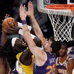 Los Angeles Lakers center Montrezl Harrell, center, shoots as Phoenix Suns guard E'Twaun Moore, left, and forward Dario Saric defend during the first half of an NBA basketball game Tuesday, March 2, 2021, in Los Angeles. (AP Photo/Mark J. Terrill)