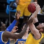Michigan forward Austin Davis grabs a rebound over UCLA forward Kenneth Nwuba, left, during the second half of an Elite 8 game in the NCAA men's college basketball tournament at Lucas Oil Stadium, Tuesday, March 30, 2021, in Indianapolis. (AP Photo/Michael Conroy)