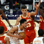 Phoenix Suns guard Devin Booker (1) drives between Atlanta Hawks forwards Solomon Hill (18) and Tony Snell (19), guard Bogdan Bogdanovic (13), center Clint Capela (15) and guard Trae Young (11) during the second half of an NBA basketball game, Tuesday, March 30, 2021, in Phoenix. Phoenix won 117-110. (AP Photo/Rick Scuteri)