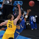 UCLA guard Tyger Campbell (10) drives to the basket ahead of Michigan guard Franz Wagner (21) during the second half of an Elite 8 game in the NCAA men's college basketball tournament at Lucas Oil Stadium, Tuesday, March 30, 2021, in Indianapolis. (AP Photo/Michael Conroy)
