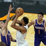 Orlando Magic center Khem Birch, center, gets off a shot against Phoenix Suns forward Dario Saric, left, and guard Devin Booker (1) during the second half of an NBA basketball game, Wednesday, March 24, 2021, in Orlando, Fla. (AP Photo/John Raoux)