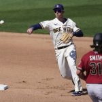 Milwaukee Brewers shortstop Daniel Robertson, left, throws to first for a double play during the fourth inning of a spring training baseball against the Arizona Diamondbacks game Friday, March 19, 2021, in Phoenix. Arizona Diamondbacks' Caleb Smith (31) was out at second and Ketel Marte was out at first. (AP Photo/Ashley Landis)