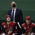 Arizona Coyotes coach Rick Tocchet watches a replay, behind Hudson Fasching (24) and Christian Dvorak (18) during the third period of the team's NHL hockey game against the Minnesota Wild on Tuesday, March 16, 2021, in St. Paul, Minn. The Wild won 3-0. (AP Photo/Hannah Foslien)