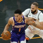 Phoenix Suns guard Devin Booker (1) looks for way around Orlando Magic guard Evan Fournier, right, during the first half of an NBA basketball game, Wednesday, March 24, 2021, in Orlando, Fla. (AP Photo/John Raoux)